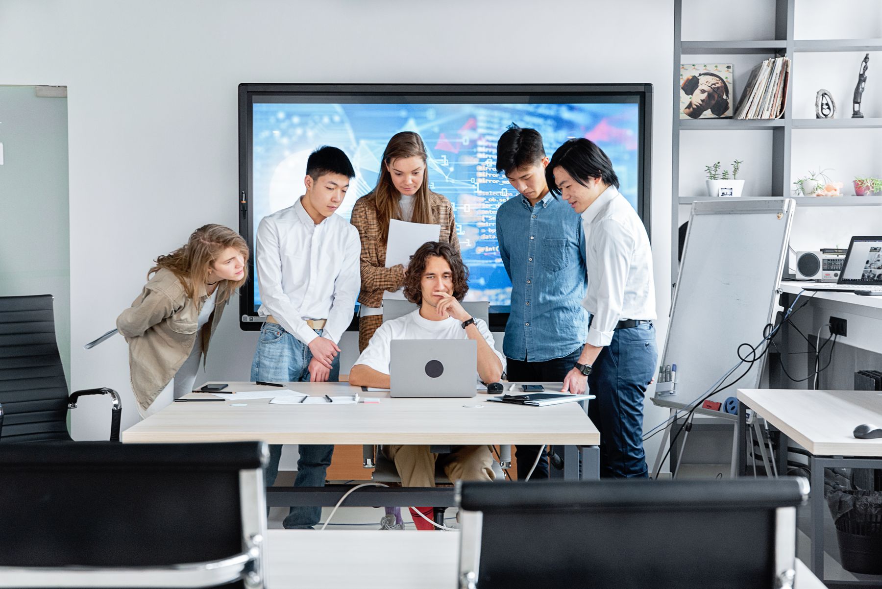 Colleagues reviewing work together around a laptop in a bright meeting room