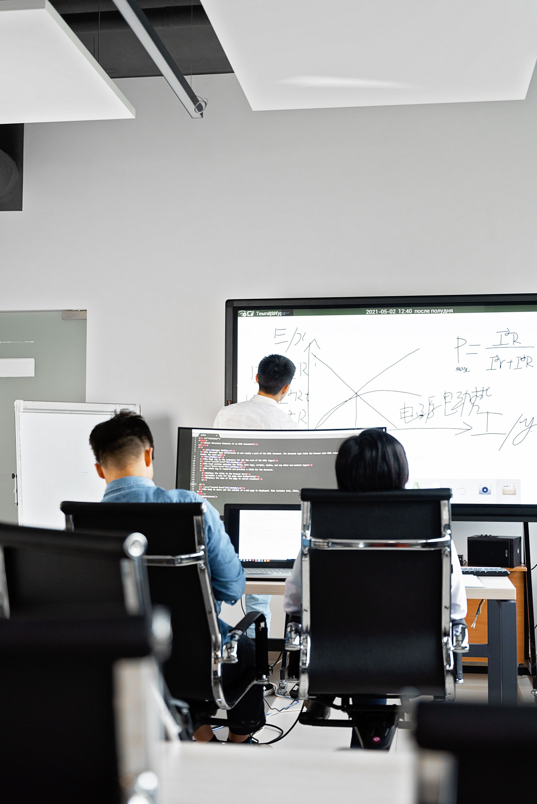 Instructor presenting at a screen while participants follow on individual workstations