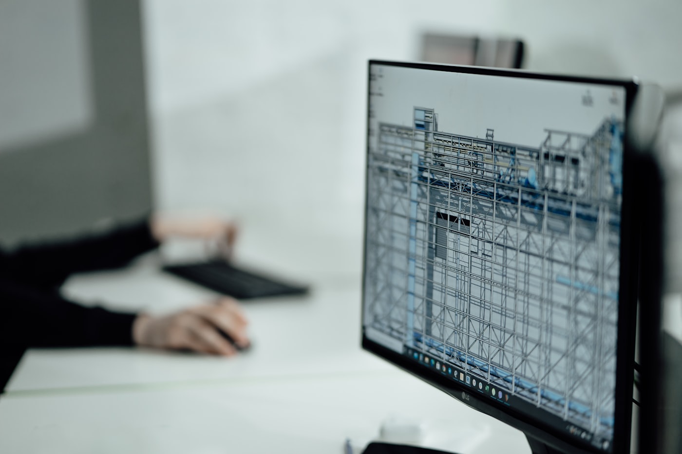 A widescreen monitor displaying a 3D CAD model of a structural steel assembly