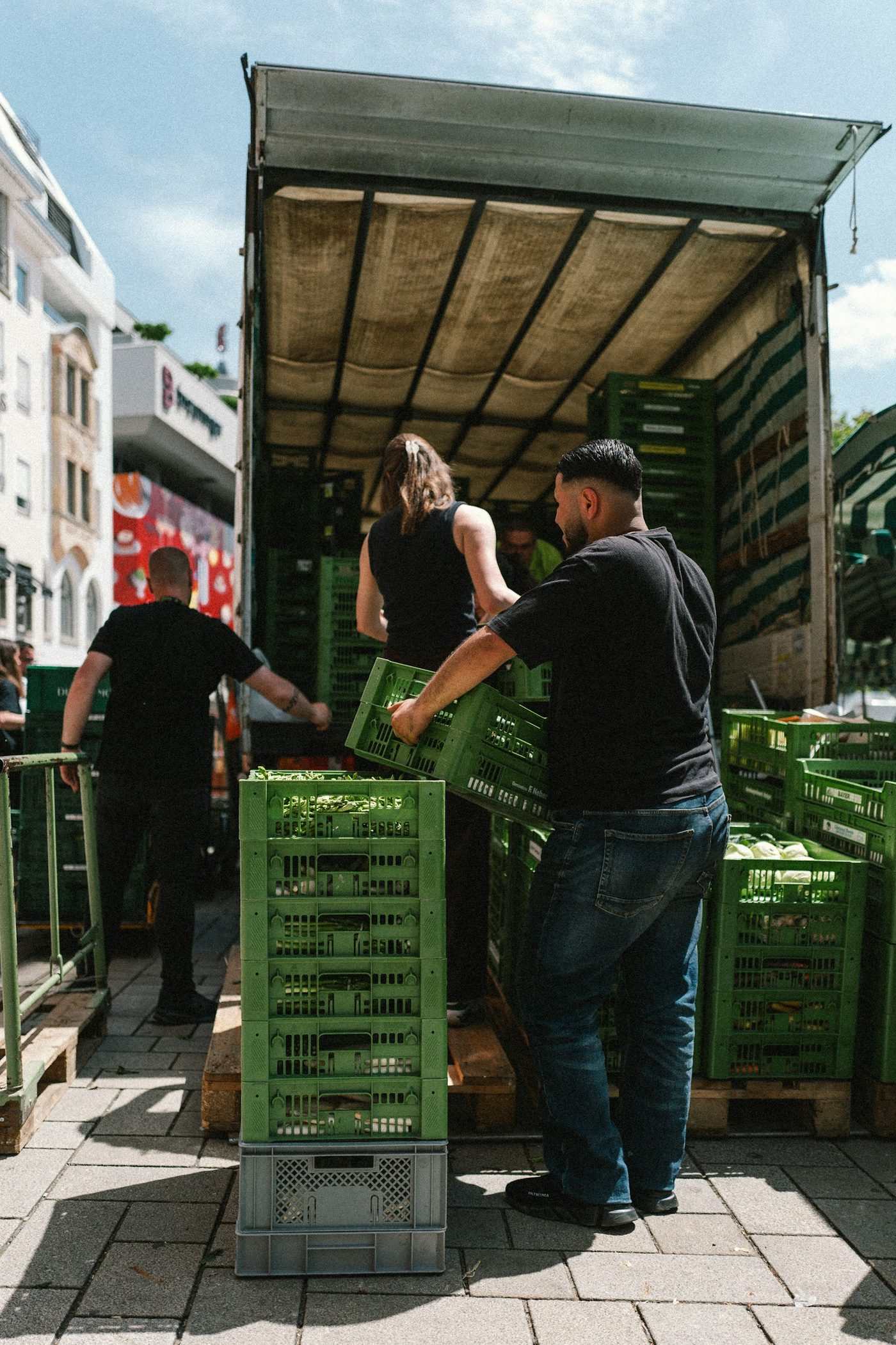 Workers unloading crates of harvested produce from a truck