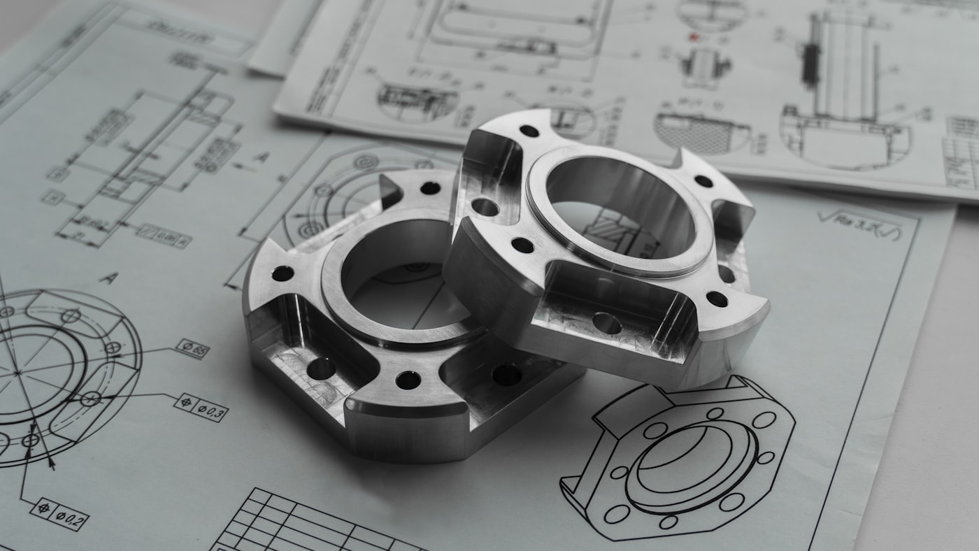 Precision-machined flange components resting on dimensioned engineering drawings