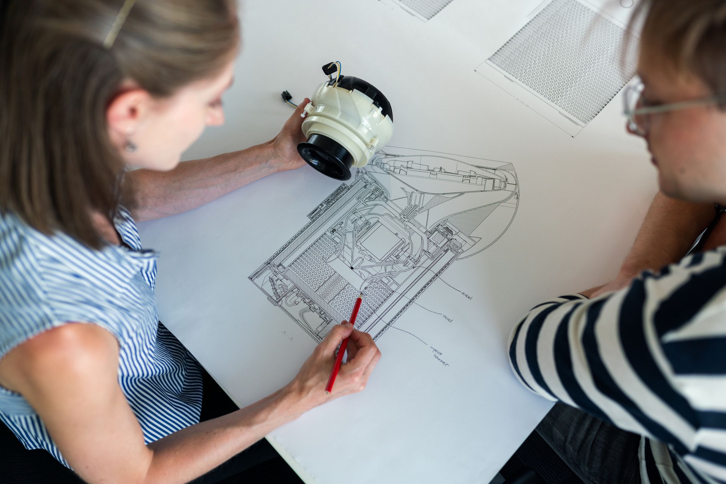 Two engineers reviewing a detailed technical cross-section drawing alongside the physical assembly