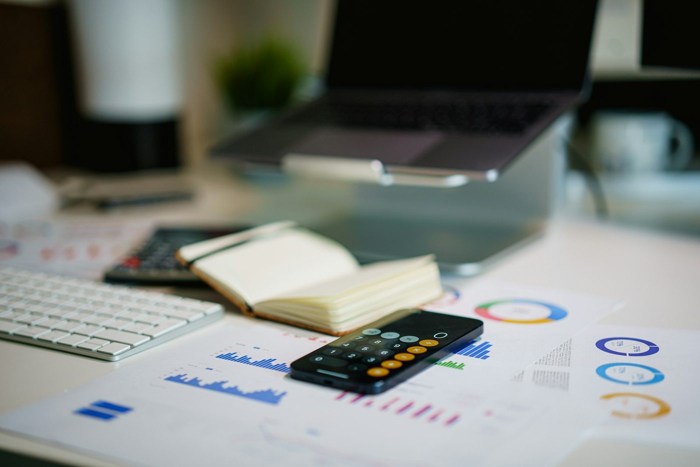 A desk with printed financial charts, a calculator and a notebook
