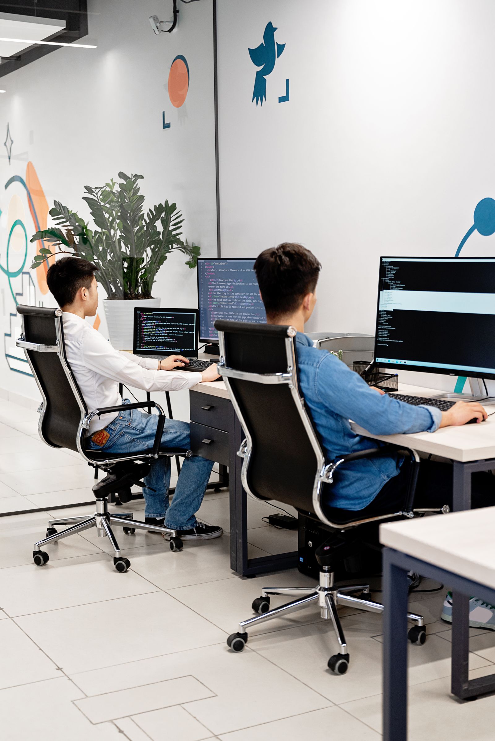 Two developers writing application code at workstations in a modern software office
