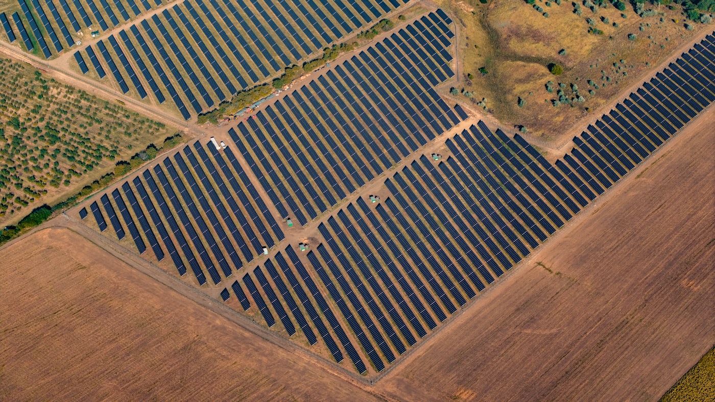 Aerial view of long rows of solar photovoltaic panels across open ground