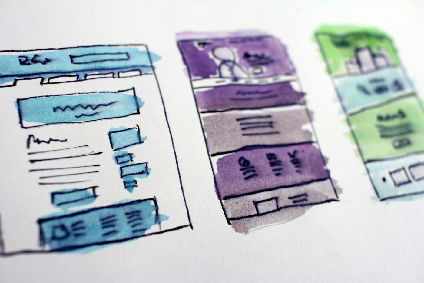 Hand-drawn website layout wireframes sketched and coloured on paper